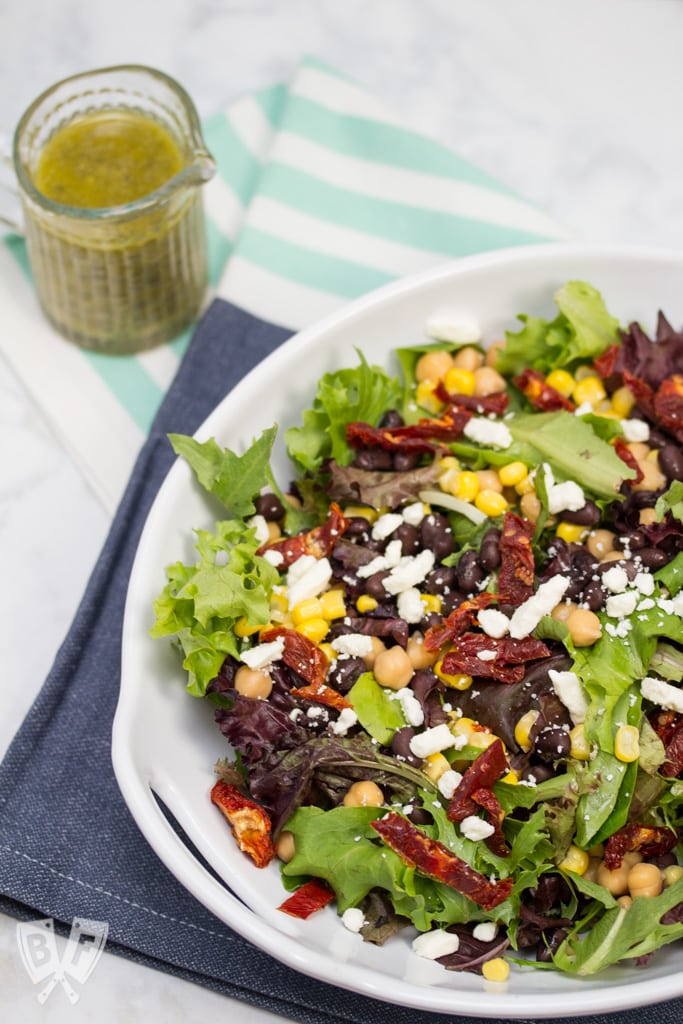 (#ad) Roma Salad with Caper-Dill Vinaigrette: Chickpeas, corn, black beans, feta cheese, + sun-dried tomatoes turn salad greens into a deliciously filling meal. Top it with a tangy homemade vinaigrette! #CookingWithCoke #CollectiveBias