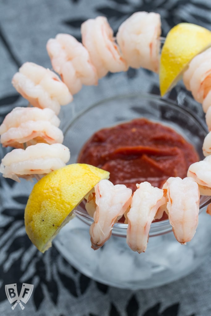 Shrimp cocktail arranged around a glass with lemon slices.