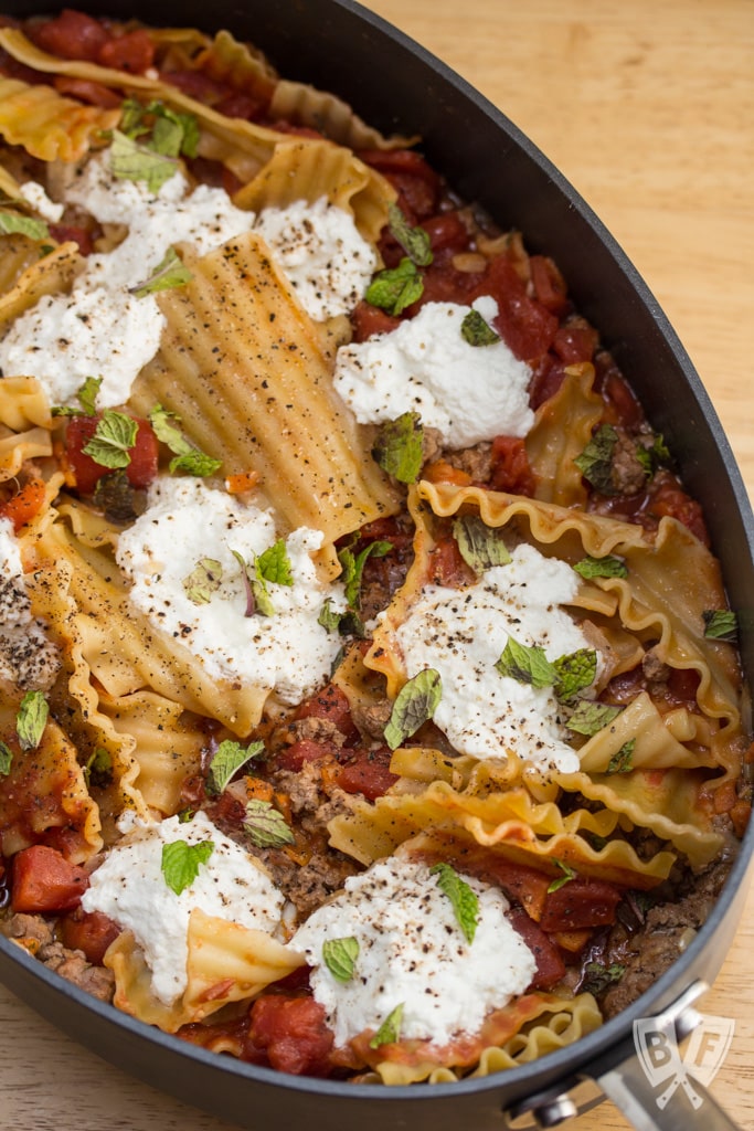 Overhead view of a skillet lasagna with lamb, ricotta, and mint.