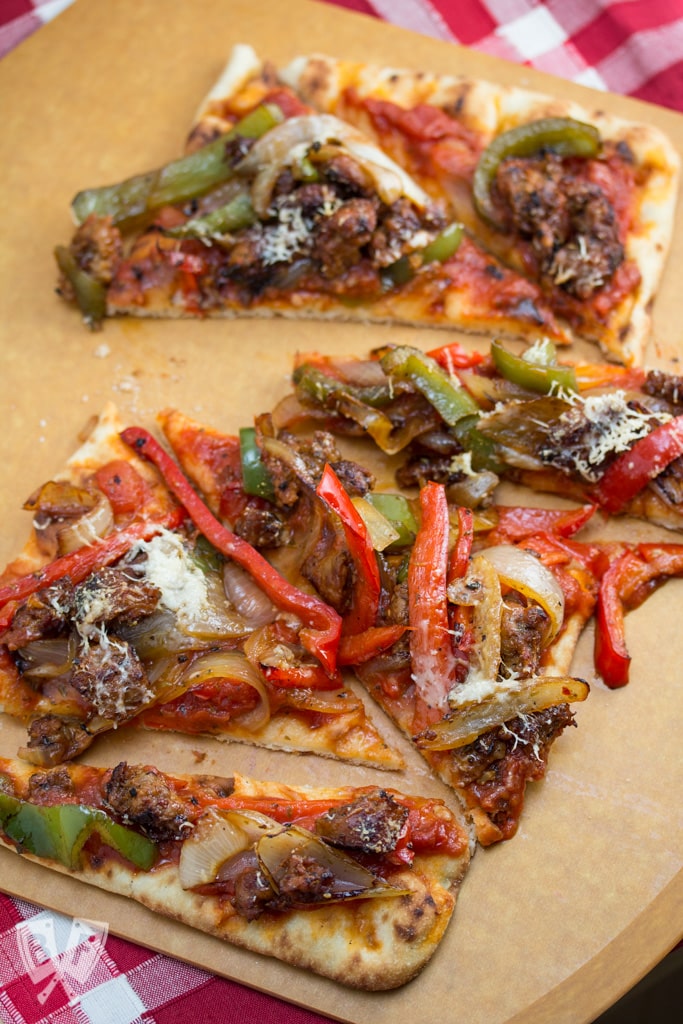 Sliced pizza topped with Italian sausage and peppers.