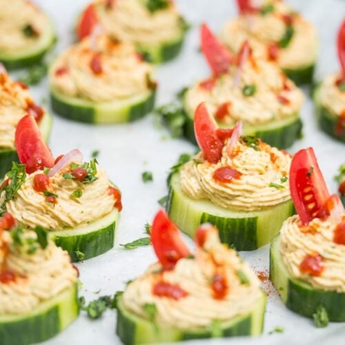 Close up of a few cucumber slices topped with a spiced chickpea purée.