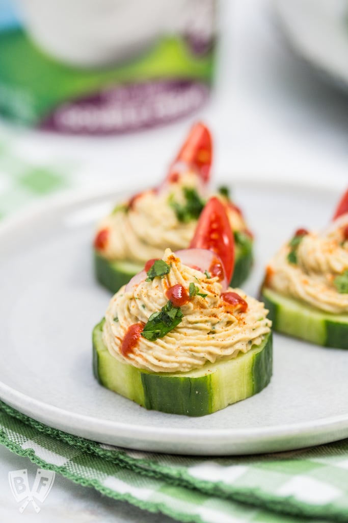 Close up of a plate with a few cucumber slices topped with a spiced chickpea purée.