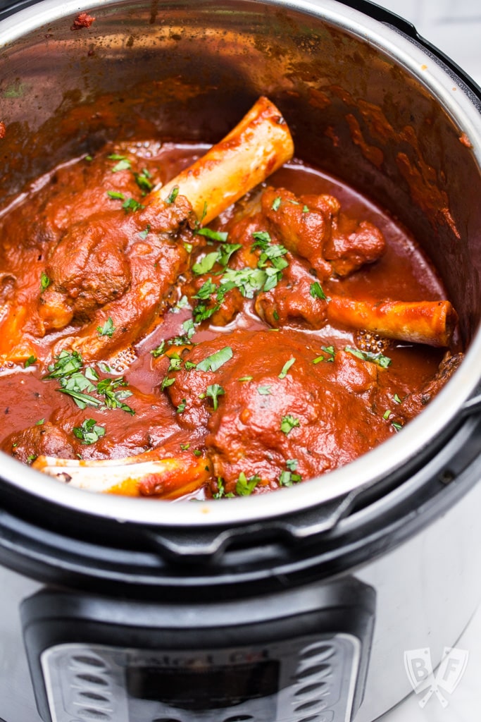 Overhead shot of lamb shanks with tomato sauce in an Instant Pot.