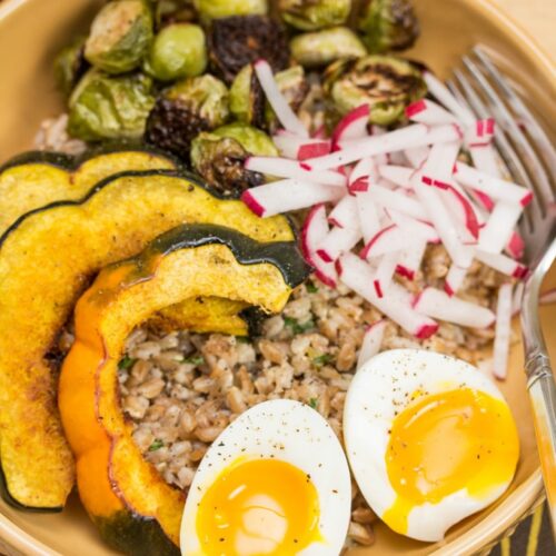 Overhead view of grain bowls with roasted veggies and soft-cooked eggs.