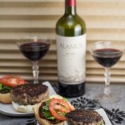 Burgers served alongside glasses of red wine.