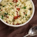 Bowl of couscous with sun-dried tomatoes and parsley.