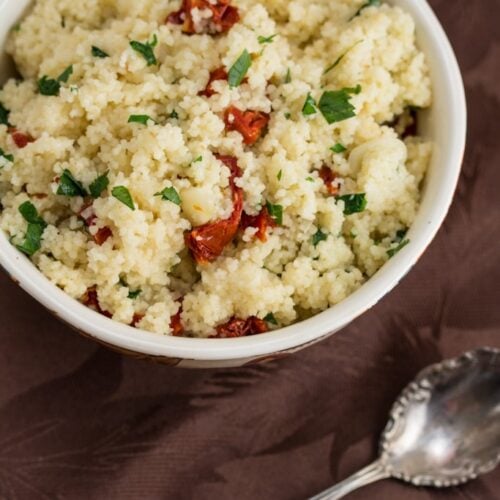 Bowl of couscous with sun-dried tomatoes and parsley.