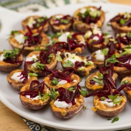 A plate of mini potato skins topped with cheese and shredded beets.