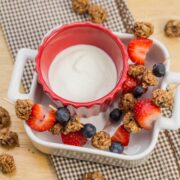 Skewered granola bites with fruit and a yogurt dipping sauce.