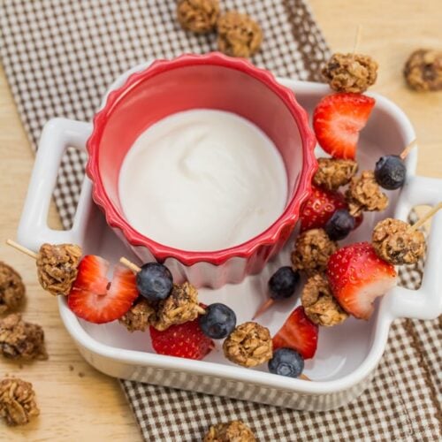 Skewered granola bites with fruit and a yogurt dipping sauce.