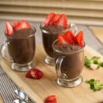 Glasses of chocolate pudding garnished with sliced strawberries.