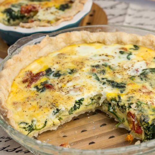 Mediterranean quiches on a table with a slice taken out.