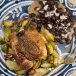Plate of chicken thigh with brussels sprouts and black beans.