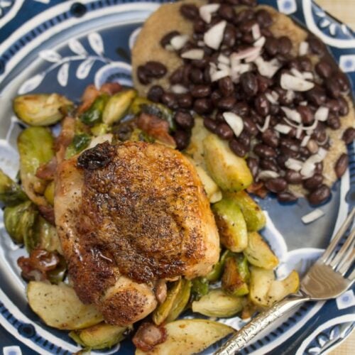 Plate of chicken thigh with brussels sprouts and black beans.