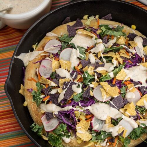 Deep dish southwest salad pizza in a cast iron skillet with dressing alongside.