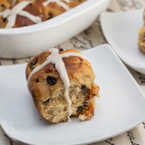 Close up of a hot cross bun with dripping icing.