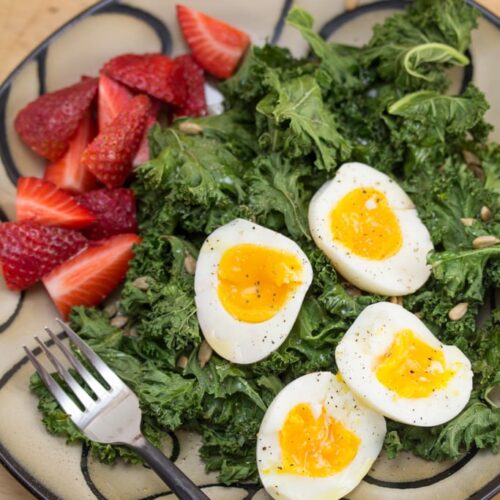 A plate of salad with eggs and strawberries.