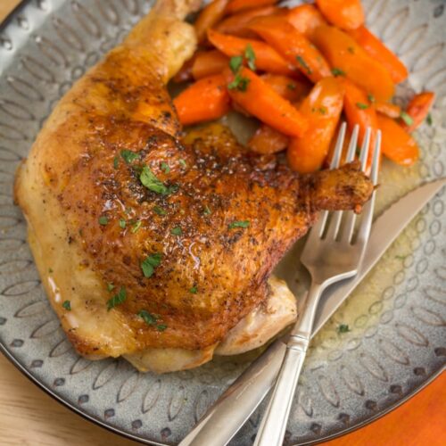 A plate of chicken and roasted carrots.