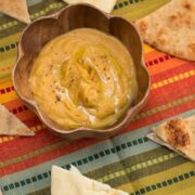 Bowl of squash hummus with pita bread alongside.