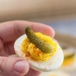 Close-up of a deviled egg topped with a cornichon.