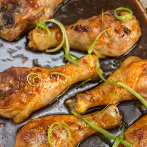 Overhead view of chicken drumsticks in a baking dish coated in sauce.