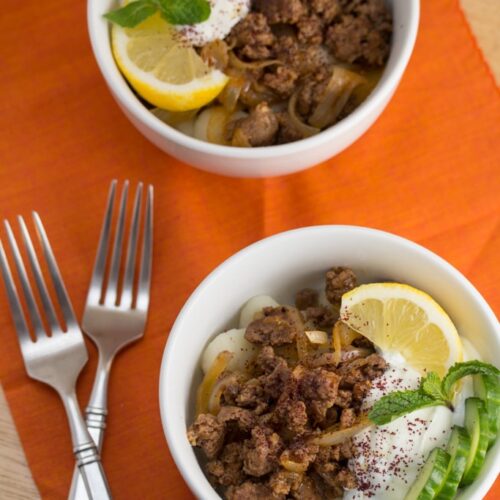 Bowls of spiced lamb over gnocchi with yogurt sauce.