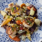 A plate of seared scallops with roasted vegetables and popped sorghum.