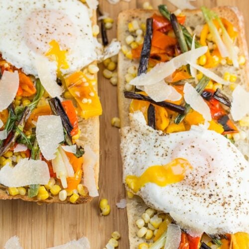 Overhead view of 2 veggie pizzas on ciabatta with fried eggs on top.