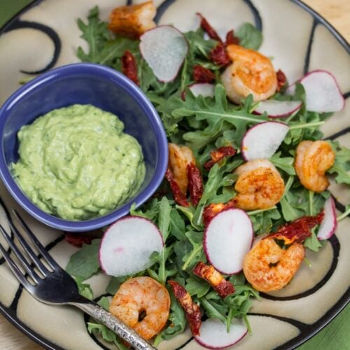 Salad with shrimp and a small bowl of green goddess dressing.