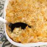 Casserole dish of lobster mac and cheese with a spoon grabbing a serving.