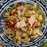 Colorful pasta on a plate topped with shaved Parmesan cheese.