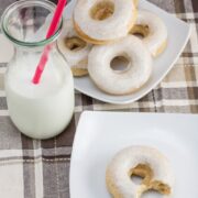 Overhead view of 2 plates of douts and a glass of milk.