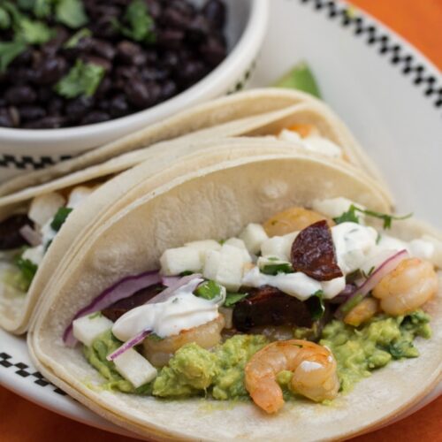 Shrimp tacos and black beans on a plate.