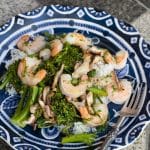 A plate of shrimp with mushrooms and broccolini.