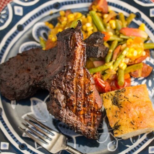 A plate of smoked ribs with vegetables and bread.