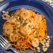 A plate of sweet potato noodles topped with shrimp and coconut curry sauce.