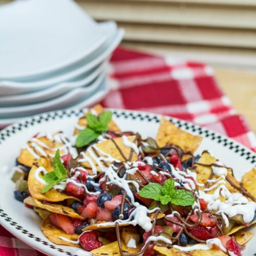 Dessert nachos topped with fruit and mint sprigs.