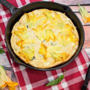 Overhead view of a squash blossom frittata in a cast iron skillet.