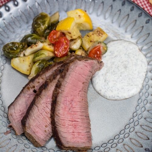 Chimichurri Marinated London Broil on a plate with sautéed veggies.