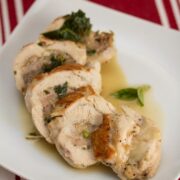 A plate of sliced, stuffed chicken on top of gravy.