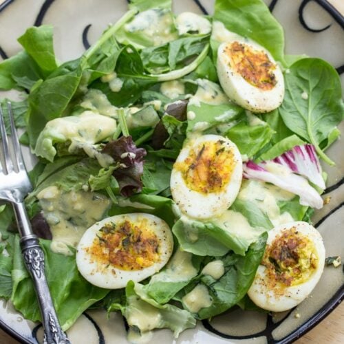 A plate of salad topped with crispy deviled eggs.