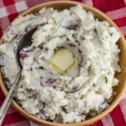 A bowl of mashed potatoes with melting butter in the center.