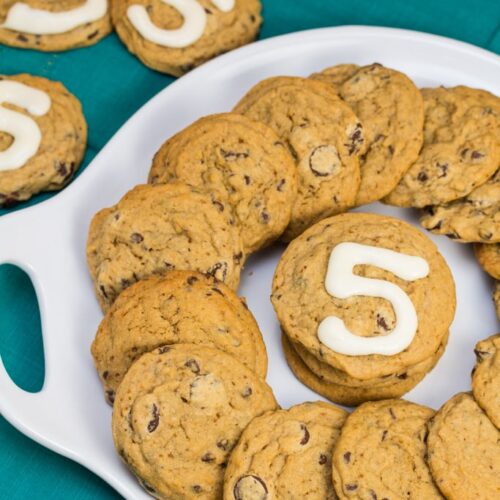 Platter of chocolate chip cookies with the number 5 written in icing on some of them.