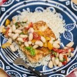 A plate of pork scallopini with white bean tomato salad and rice.