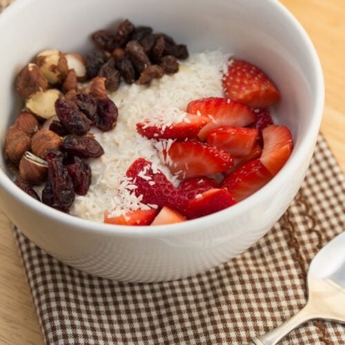 Bowl of muesli topped with fruit and nuts.