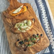 Overhead view of 3 types of crostini on a cutting board.