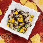 Overhead shot of a bowl of Mango, Jicama + Black Bean Salsa with tortilla chips.