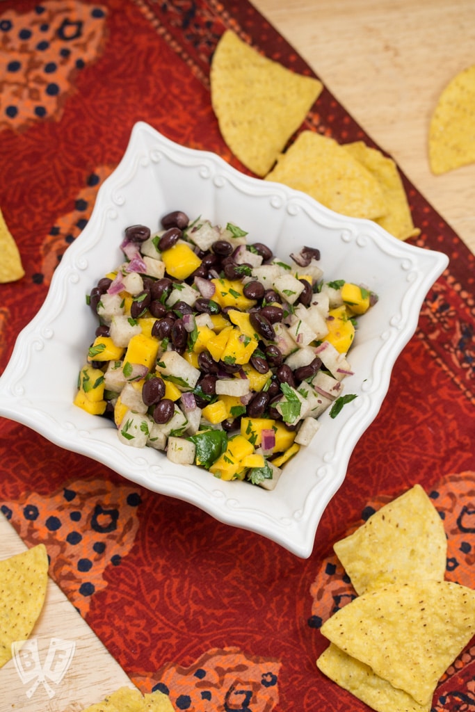 Overhead shot of a bowl of Mango, Jicama + Black Bean Salsa with tortilla chips.