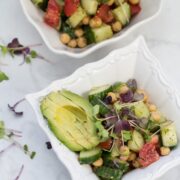 A bowl of chickpea salad with avocado and microgreens.