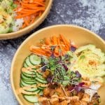 Two spicy salmon poke bowls with rice and colorful toppings.